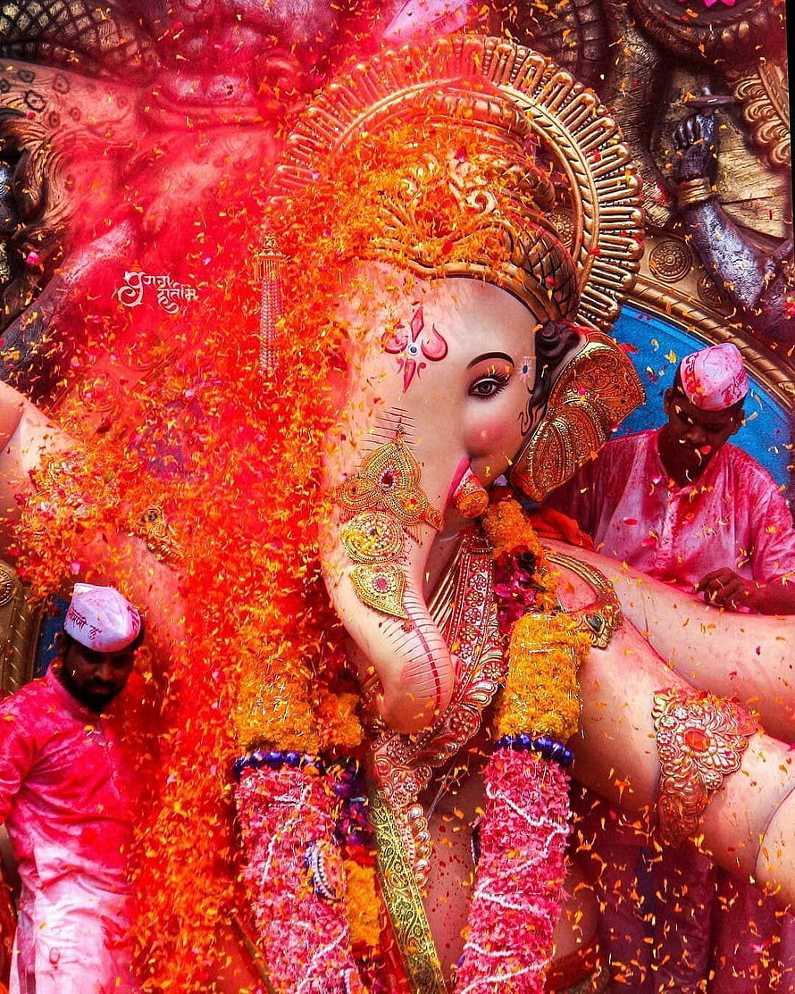 Vibrant Ganesha Idol Covered in Marigold Petals During Festival Celebration HD phone wallpaper
