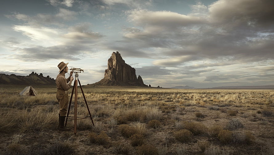 Historic Surveyor with Tripod Theodolite in Vast Desert Landscape HD wallpaper