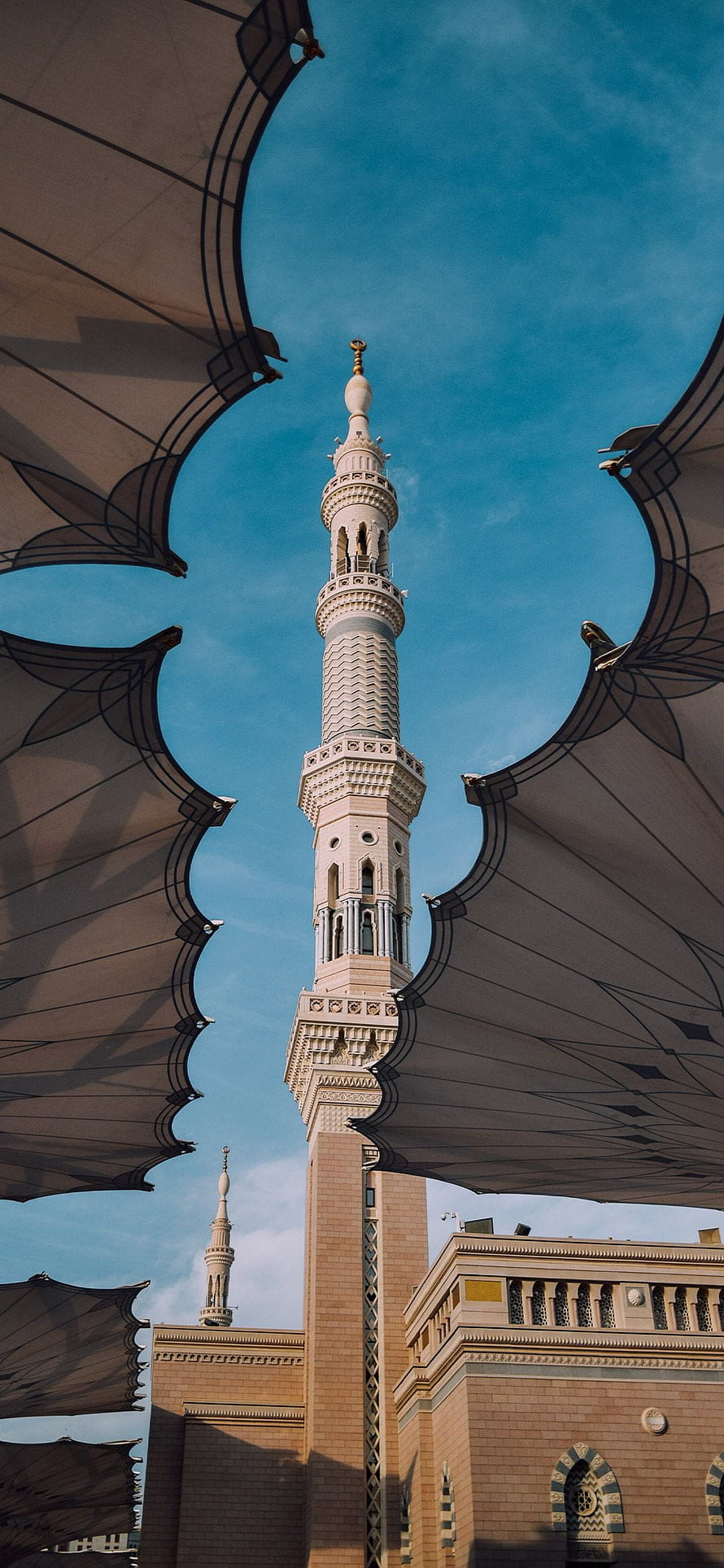 Grand Minaret of Masjid al-Haram Rising Above Tented Canopies Under a Clear Blue Sky HD phone wallpaper