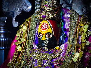 Ornate Hindu Deity Statue Adorned With Gold Coins, Jewels, and Traditional Sacred Markings HD wallpaper