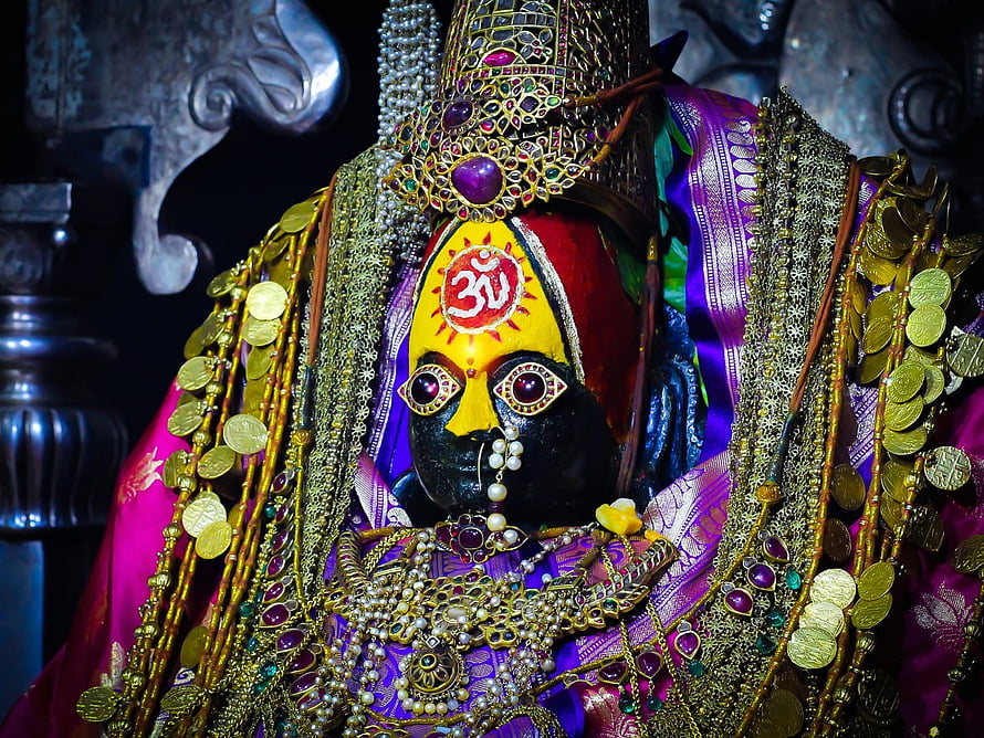 Ornate Hindu Deity Statue Adorned With Gold Coins, Jewels, and Traditional Sacred Markings HD wallpaper