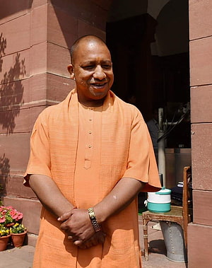 Yogi Adityanath in traditional orange kurta standing outdoors near a stone building HD phone wallpaper