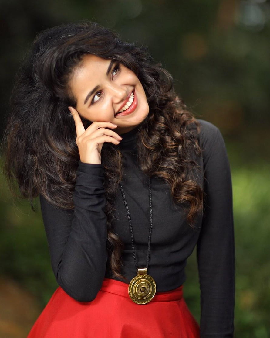 Portrait of a smiling woman with curly hair wearing a black top and red skirt, Anupama Parameswaran HD phone wallpaper