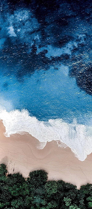 Aerial View of Turquoise Ocean Waves Crashing on Sandy Beach with Green Forest HD phone wallpaper