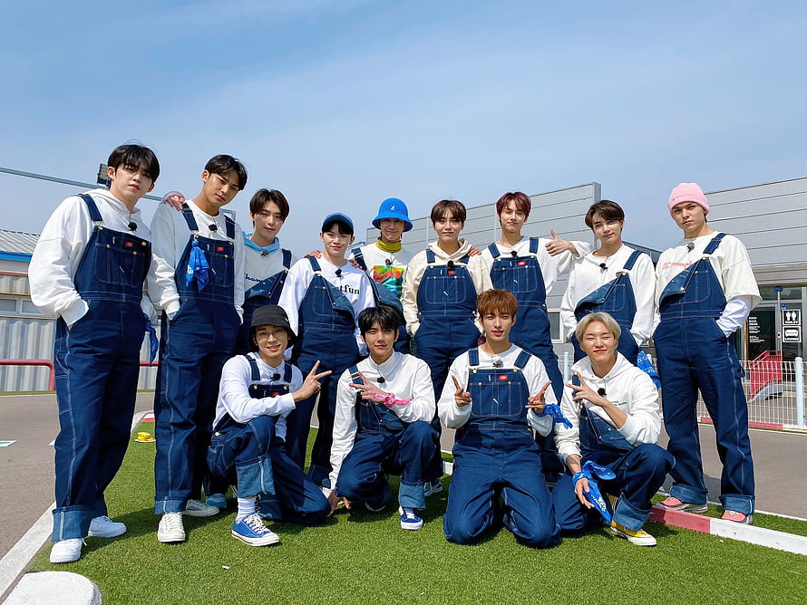 SEVENTEEN members posing in matching denim overalls on a sunny outdoor field HD wallpaper