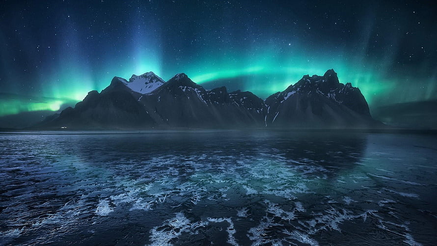 Iceland Night Sky with Green Aurora Borealis Over Snow-Capped Mountains and Frozen Water HD wallpaper
