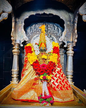 Ornate Hindu Goddess Statue Adorned with Red and Yellow Flowers in Temple Shrine HD phone wallpaper
