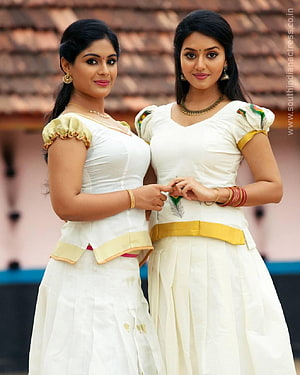 Two women in traditional white and gold Indian attire posing together outdoors HD phone wallpaper