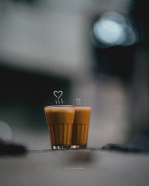Two glasses of hot chai with heart-shaped steam rising against a moody blurred background HD phone wallpaper