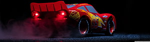 Lightning McQueen from Cars 3 performing a dramatic drift with tire smoke on a dark track HD wallpaper