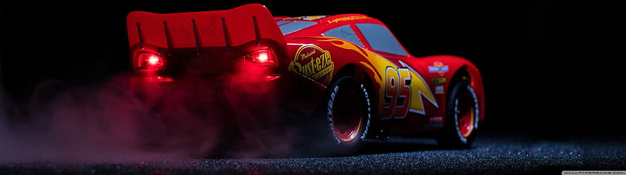 Lightning McQueen from Cars 3 performing a dramatic drift with tire smoke on a dark track HD wallpaper