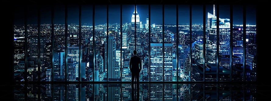 Silhouette of a Man Standing in a High-Rise Office Overlooking a Glowing City Skyline at Night, Dual Monitor HD wallpaper