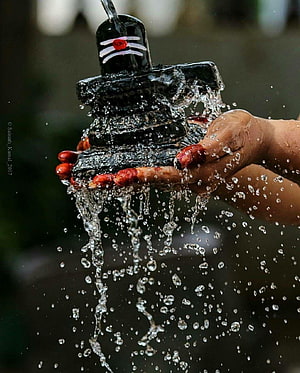 Devotee Performing Abhishekam Ritual on Shiva Lingam with Water and Red Vermillion HD phone wallpaper