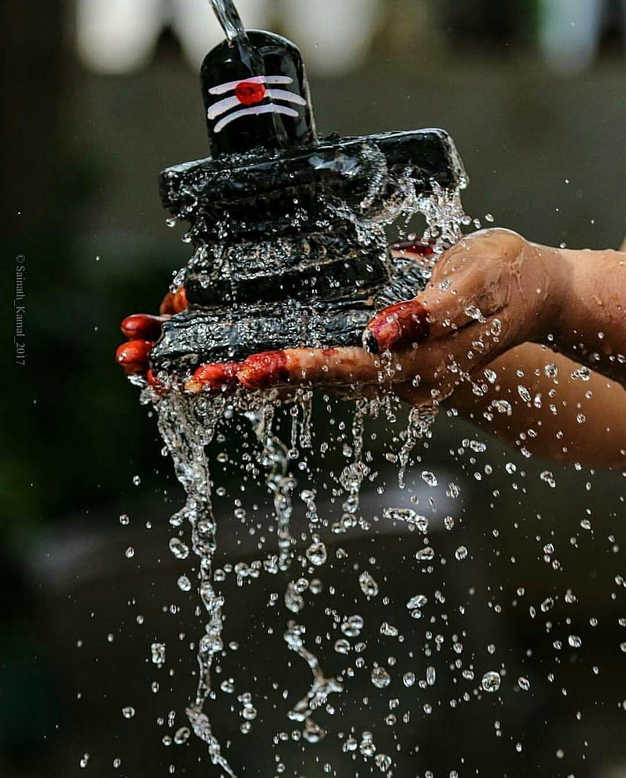 Devotee Performing Abhishekam Ritual on Shiva Lingam with Water and Red Vermillion HD phone wallpaper
