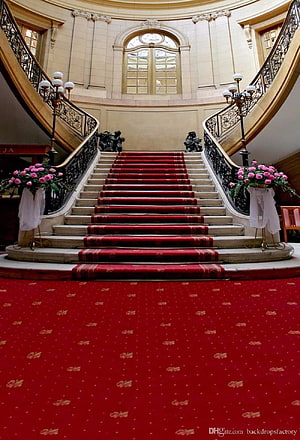Grand Marble Staircase with Red Carpet and Pink Floral Arrangements in an Elegant Hall HD phone wallpaper