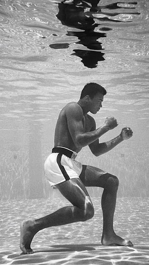 Muhammad Ali in a boxing stance underwater in a black and white photograph HD phone wallpaper