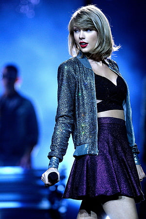 Taylor Swift performing on stage in a sparkly jacket and purple skirt HD phone wallpaper
