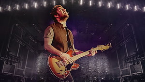 John Mayer performing live on stage with a sunburst electric guitar under dramatic concert lighting HD wallpaper