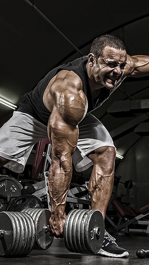 Muscular Athlete Performing Heavy Dumbbell Curl in Dark Gym Setting HD phone wallpaper