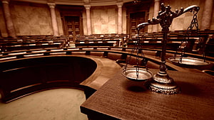 Ornate Scales of Justice on a Wooden Desk in a Grand Courtroom HD wallpaper