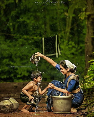 Mother Pouring Water on Child in Traditional Village Setting HD phone wallpaper