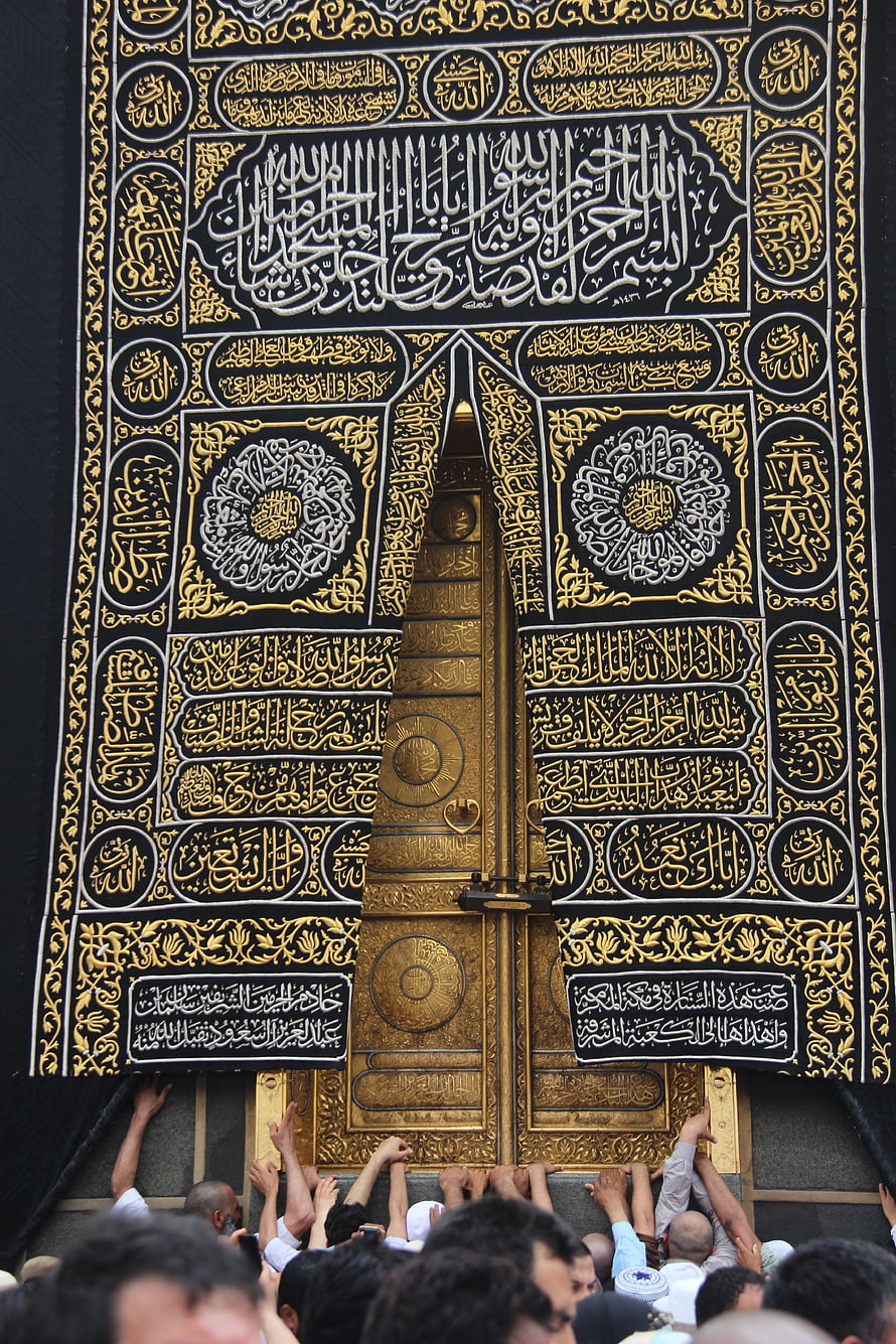 Ornate Golden Kaaba Door with Intricate Arabic Calligraphy and Pilgrims Reaching Toward the Sacred Entrance HD phone wallpaper
