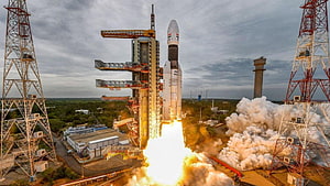 ISRO GSLV Mk III rocket launch with bright exhaust plume and launch tower HD wallpaper