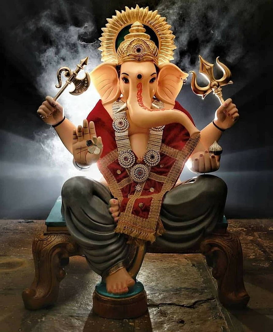 Ganesha seated on ornate throne holding trident and axe with radiant golden halo HD phone wallpaper