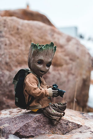 Baby Groot Doll with Camera and Backpack Sitting on a Rocky Outcrop HD phone wallpaper