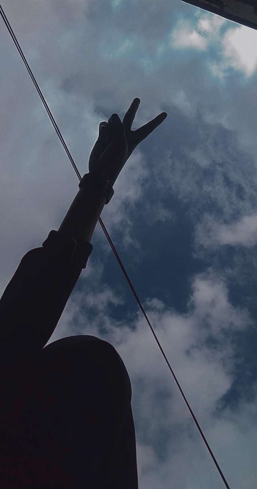 Silhouette of a hand making a peace sign against a cloudy blue sky HD phone wallpaper