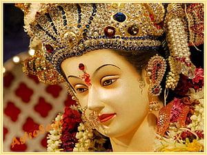 Close-up of Goddess Lakshmi idol adorned with jeweled crown, nose ring, and floral garlands HD wallpaper