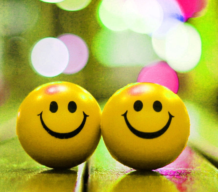 Two Yellow Smiley Face Orbs with Bokeh Lights on a Green Surface HD wallpaper