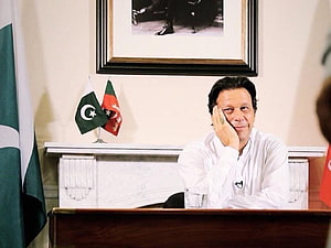 Imran Khan sitting at a desk with Pakistan and Afghanistan flags in the background HD wallpaper