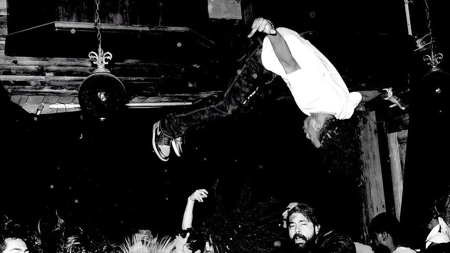 Playboi Carti performing an acrobatic flip over the crowd at a live concert HD wallpaper